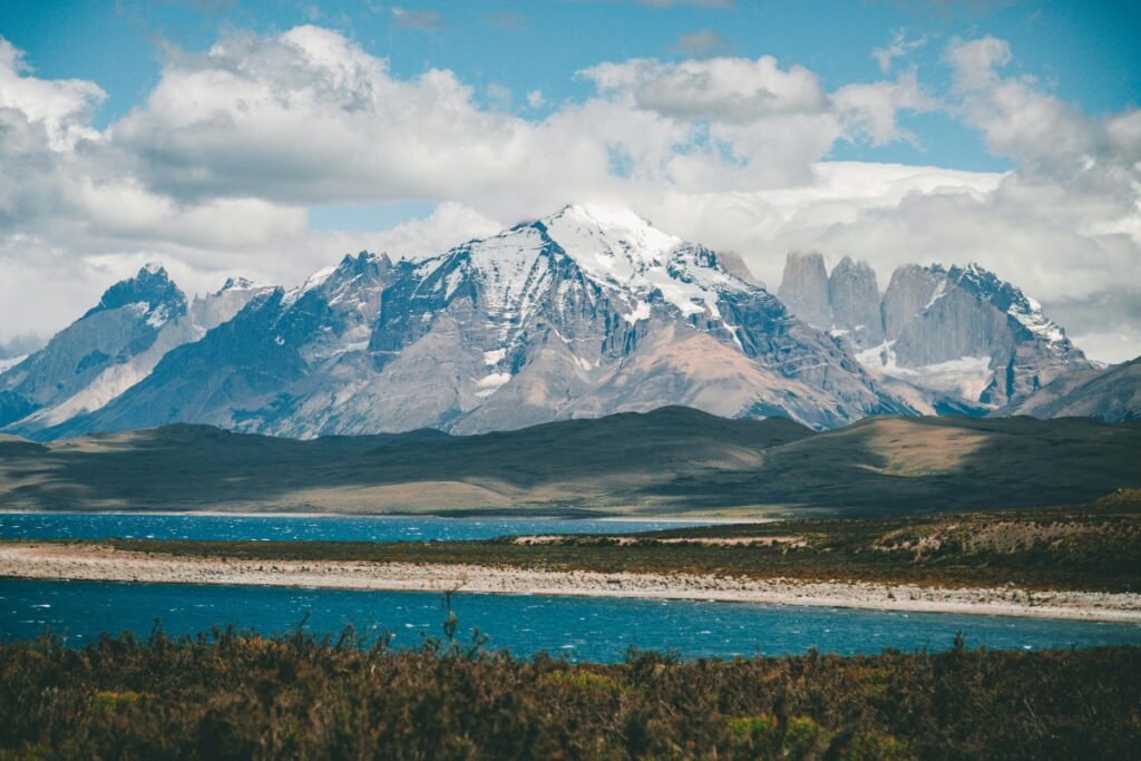 Esta imagen presenta un impresionante paisaje de montañas nevadas, con picos que se elevan majestuosamente sobre un extenso lago de color azul intenso. Las nubes flotando en el cielo azul completan la escena. Para los usuarios de Twitter en Chile que deseen hacer que sus publicaciones se vuelvan virales, utilizando hashtags relacionados con los hermosos paisajes naturales de Chile, como los que se ven en esta foto, siguiendo las estrategias de "Twitter en Chile Cómo usar hashtags para viralizar", puede ser una forma efectiva de aumentar la visibilidad y la interacción en la plataforma.