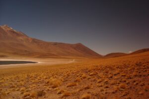 Esta imagen muestra un paisaje desértico en Chile, con extensas laderas cubiertas de hierba seca y una montaña imponente al fondo. Una laguna reluce en la distancia, contrastando con el terreno marrón. Esta vista natural puede ser una fuente de inspiración para aquellos que buscan crear contenido en YouTube en Chile. Aprendiendo los trucos de &ldquo;YouTube en Chile Cómo Crecer y Monetizar Tu Canal&rdquo;, los creadores pueden aprovechar la belleza de paisajes como este para atraer a más espectadores y alcanzar el éxito en su canal.